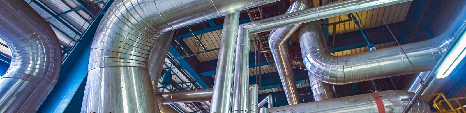 Industrial ventilation ductwork and stainless steel piping inside a modern manufacturing facility Industrial ventilation ductwork and stainless steel piping inside a modern manufacturing facility